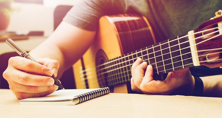 Romantic Guitar. Writing note musician or married man plays guitar on a black sofa at home.